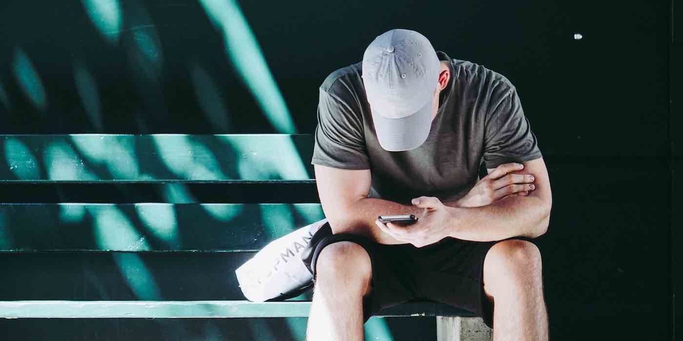 Disaster Distress Helpline Person with cell phone sitting on bench