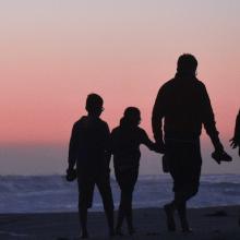 Family walking on beach at sunset
